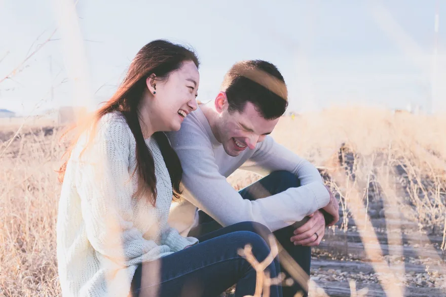 Young couple laughing together in a field of tall grass