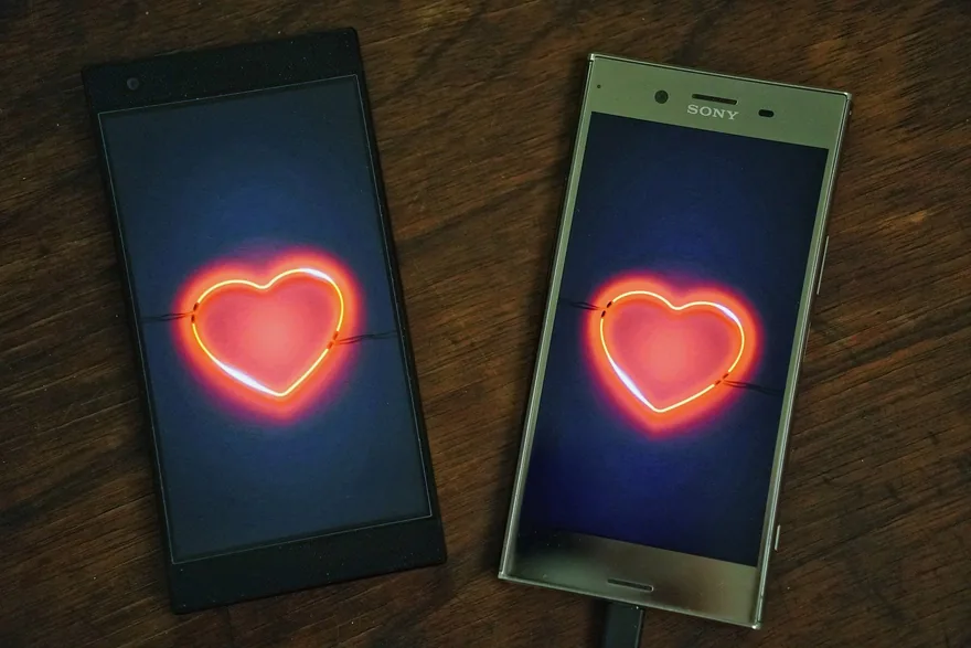Two smartphones side by side, each showing a glowing red heart