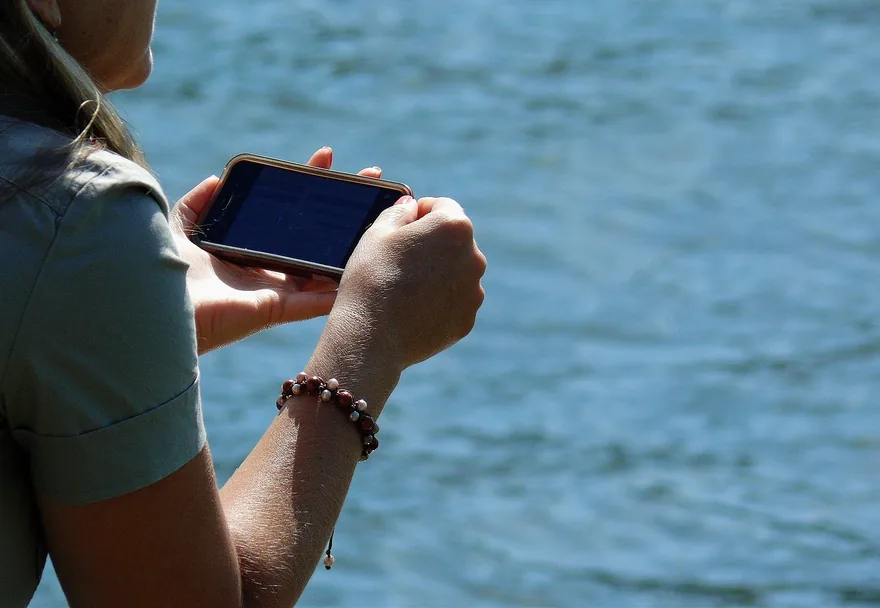 Person holding a phone with the sea in the background