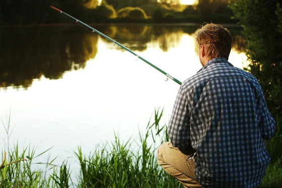 Man fishing at a lake in the late afternoon sun