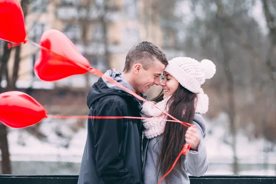 Happy couple embracing among red heart-shaped balloons