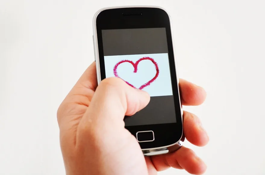 Hand holding a phone with a heart drawn on the screen