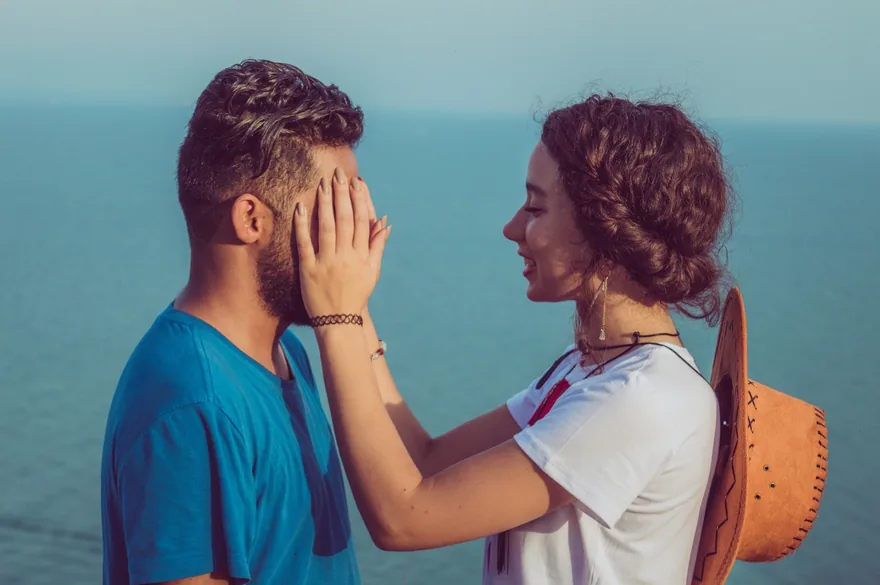 Woman gently holding a man's face as they smile at each other